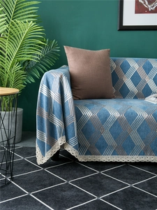 Detailed view of blue chenille sofa cover with geometric diamond patterns and white lace edges