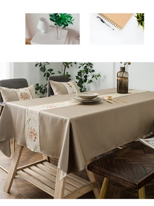 Detailed close-up of beige table runner and pillows with pink rose embroidery floral decor