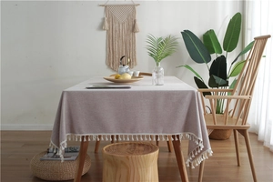 Detail of light pink linen-texture tablecloth with decorative white tassel edges