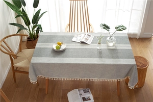 Close-up of gray linen table runner with white lace stitching and elegant fringe tassels