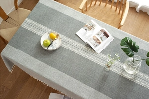 Detail of grey jacquard table runner featuring white wave embroidery and cotton tassels
