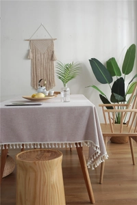 Detail of light purple linen tablecloth featuring white tassel fringe in a cozy home setting