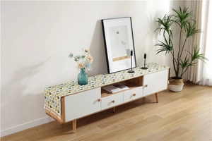 Close-up of geometric pattern table runner with white decorative fringe on wooden cabinet