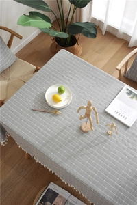 Close-up of gray checkered tablecloth with white tassel fringe and jacquard texture