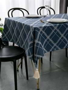 Close-up of blue rectangular tablecloth with white grid pattern and beige tassels