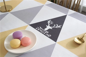Detail of Nordic geometric table cloth with yellow and gray triangles and deer head print