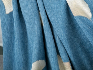 Close-up of thick chenille fabric with blue ginkgo leaf patterns and woven texture