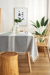 Close-up of grey jacquard table runner with white woven texture and elegant tassel edges