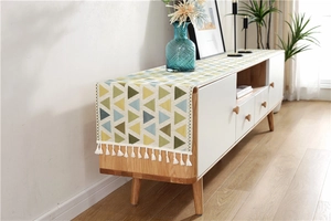 Detail view of colorful geometric chenille table runner with white cotton tassels