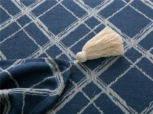 Close-up of blue jacquard tablecloth featuring white diamond patterns and elegant tassel