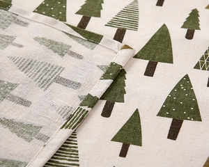 Detail of fabric tablecloth with green Christmas tree patterns and stitched edges