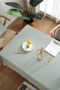 Detailed macro view of green checkered tablecloth with white tassels on wood table