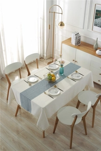 Detail of waterproof dining table runner with blue herringbone pattern and white tassels