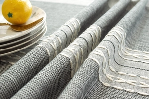 Close-up of grey jacquard table runner with white stitching and textured linen fabric