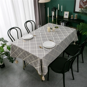Modern grey geometric jacquard tablecloth with elegant white tassels on a dining table