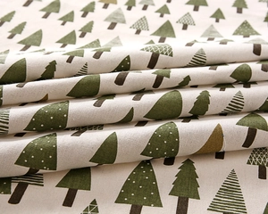 Detail of soft linen fabric showing green evergreen tree patterns and woven texture