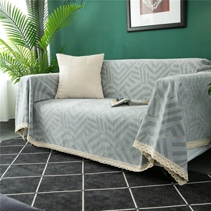 Detail of gray chenille sofa cover with geometric leaf pattern and white lace edge trim
