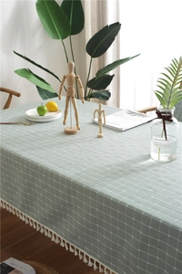 Close-up of sage green plaid tablecloth featuring elegant white tassel fringe edges