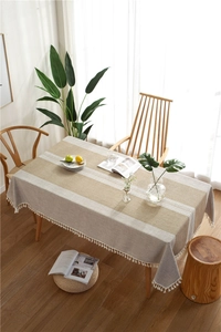 Detail of jacquard table runner with white lace insert and fringe tassels on wood surface