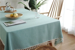 Close-up of mint green tablecloth with fringe edges and premium woven linen texture