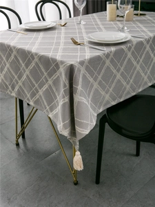Detail of gray and white checkered tablecloth with handmade tassels in a modern room