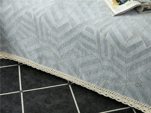 Close-up of chenille sofa cover with blue geometric patterns and beige lace edges