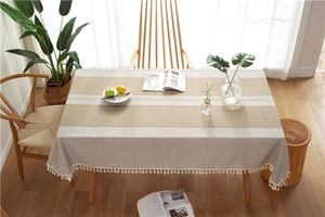 Close-up of beige and brown striped table runner with white cotton fringe tassels