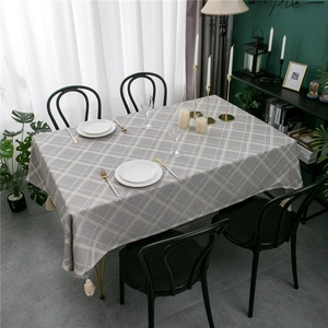 Close-up of modern grey checkered tablecloth with decorative fringe tassels and linen texture