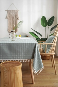 Detail of green checkered tablecloth featuring white tassel fringe and jacquard texture