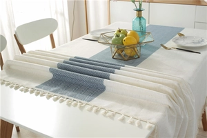 Detail of waterproof dining runner featuring navy herringbone stripes and cotton tassels