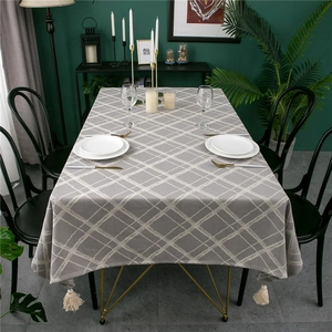 Macro detail of grey checkered linen tablecloth featuring decorative cream tassels