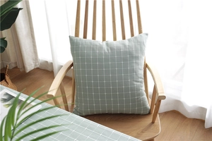 Detailed texture of a sage green checkered throw pillow on a wooden chair