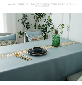 Detail of light blue cotton hemp tablecloth featuring elegant floral embroidery patterns