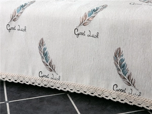 Close-up of thick chenille fabric with feather prints, Good Luck text and lace edging