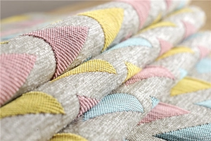 Macro view of textured chenille fabric with colorful geometric triangle pattern and tassels