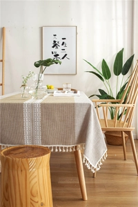 Close-up of linen jacquard table runner with delicate white embroidery and handmade tassels