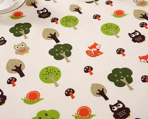 Detail of cotton tablecloth with forest cartoon patterns featuring owls and foxes