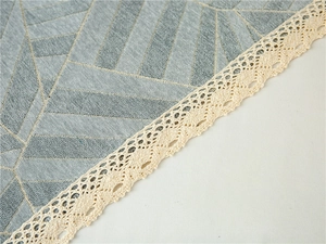 Detailed view of gray-blue chenille fabric with gold geometric patterns and lace edging