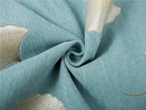 Close-up of thick teal chenille sofa cover fabric with gold jacquard leaf pattern