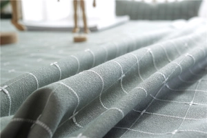 Detail of sage green plaid fabric with white cross-stitch pattern and soft drape texture