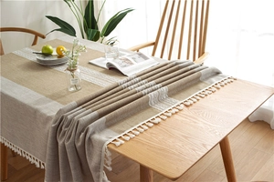 Detail of linen texture table runner with white lace insert and fringe tassels