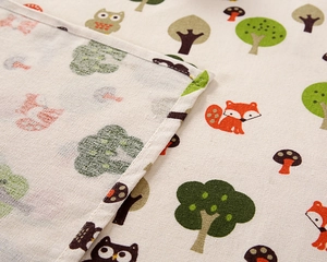 Close-up of cotton linen tablecloth with forest animals print and neat stitched edges