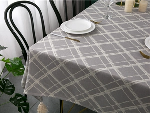 Detail of gray checkered tablecloth featuring white tassel trim and woven jacquard texture