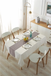 Detail of waterproof linen table runner with herringbone pattern and cream tassels decor