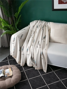 Close-up of beige chenille sofa cover with blue feather pattern and lace edge trim