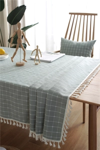 Close-up of light green checkered tablecloth featuring elegant white tassel lace edges