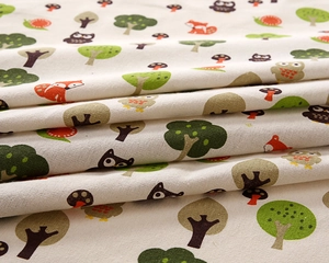 Detailed close-up of cotton linen fabric featuring forest animals and tree patterns