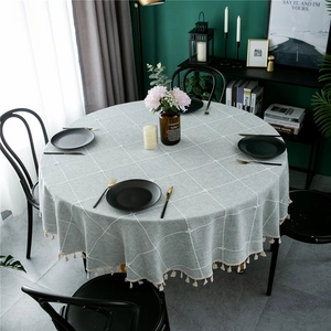 Close-up of grey and white checkered round tablecloth with elegant beige fringe tassels