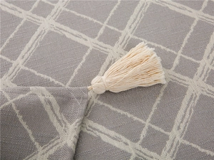Macro detail of grey checkered tablecloth fabric showing cotton texture and cream tassels
