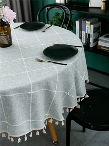 Close-up of light grey blue checkered tablecloth with soft cotton fringe tassels